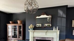 A living room with a fireplace, a yellow sofa, a brown leather armchair, and a cabinet with glass doors. - The Colonial Farmhouse with Private Boat Rental (Centreville)