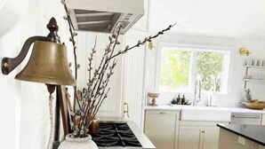 A kitchen with white cabinets, a marble countertop, a stove, and a window providing natural light. - The Colonial Farmhouse with Private Boat Rental (Centreville)