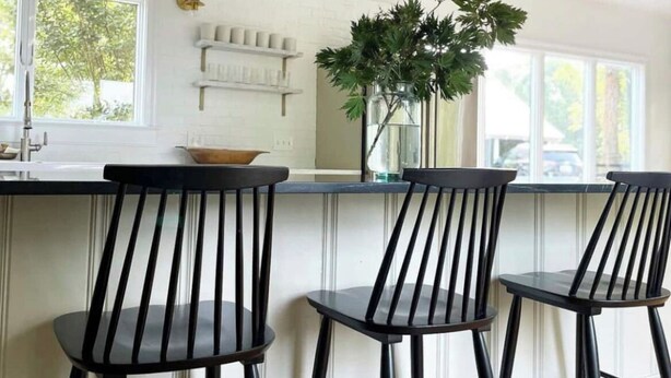 A kitchen with a white brick backsplash, a wooden countertop, and three black bar stools. - The Colonial Farmhouse with Private Boat Rental (Centreville)