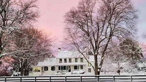 A two-story house with a snow-covered roof and a white fence in front. - The Colonial Farmhouse with Private Boat Rental (Centreville)