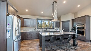A modern kitchen with a large island, stainless steel appliances, and a view of the outdoors.