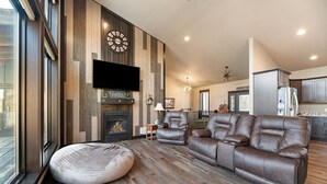 A modern living room with a large leather sofa, a round bean bag, and a fireplace.