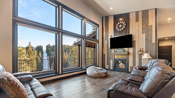 A spacious living room with large windows, a fireplace, and a leather sofa.