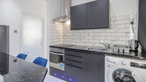 A compact kitchen with a built-in oven, a washing machine, and a sink. - Stunning Top 2 Bed Flat Tilbury Central Location (Tilbury)