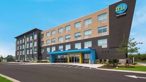 A modern hotel building with a prominent 'tru by Hilton' sign, multiple floors, and a parking lot in front. - Tru By Hilton Novi Detroit (Novi)