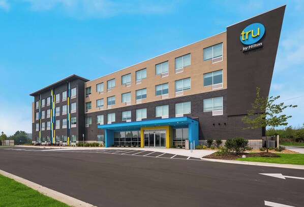 A modern hotel building with a prominent 'tru by Hilton' sign, multiple floors, and a parking lot in front. - Tru By Hilton Novi Detroit (Novi)
