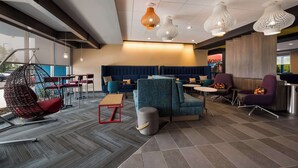 A modern lounge area with seating arrangements, a hanging chair, and pendant lighting. - Tru By Hilton Novi Detroit (Novi)