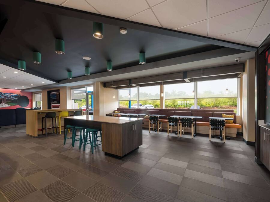 A modern restaurant with a central island, seating area, and large windows offering a view of the outdoors.