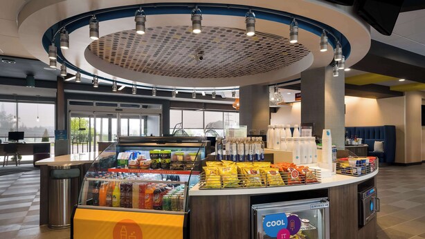 A self-service beverage station with a variety of drinks, snacks, and a refrigerated section. - Tru By Hilton Novi Detroit (Novi)