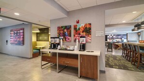 A modern breakfast area with a long counter, coffee machines, and seating. - Hampton Inn Lincoln White Mountains (Lincoln)
