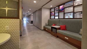A hotel lobby with a long corridor, a reception desk, a sofa with cushions, and a wall with framed pictures. - Hampton Inn Lincoln White Mountains (Lincoln)