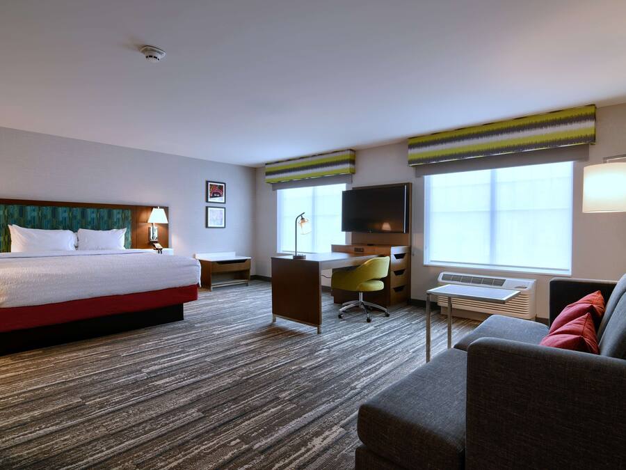 Une chambre d’hôtel avec un grand lit, un bureau, une chaise, un canapé et une télévision.