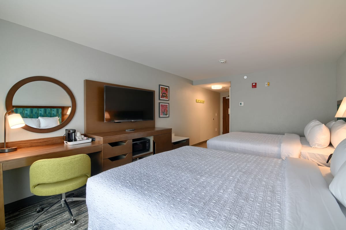 A hotel room with a bed, a desk with a chair, a television, and a microwave.