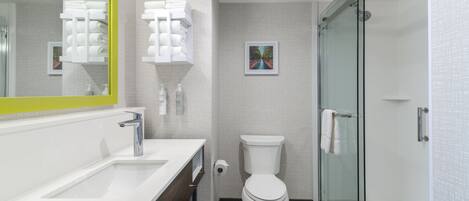 Un baño moderno con lavamanos blanco, inodoro y cabina de ducha de vidrio.