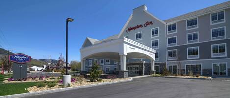 Edificio de Hampton Inn by Hilton con una entrada amplia y un estacionamiento.