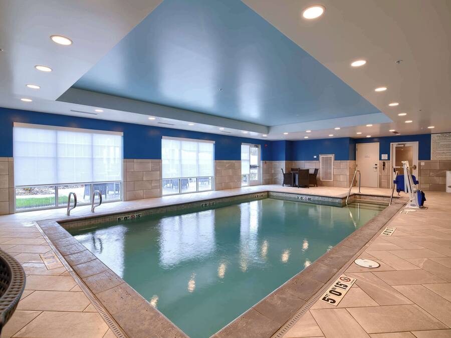 An indoor swimming pool with clear water, tiled floor, and blue walls.