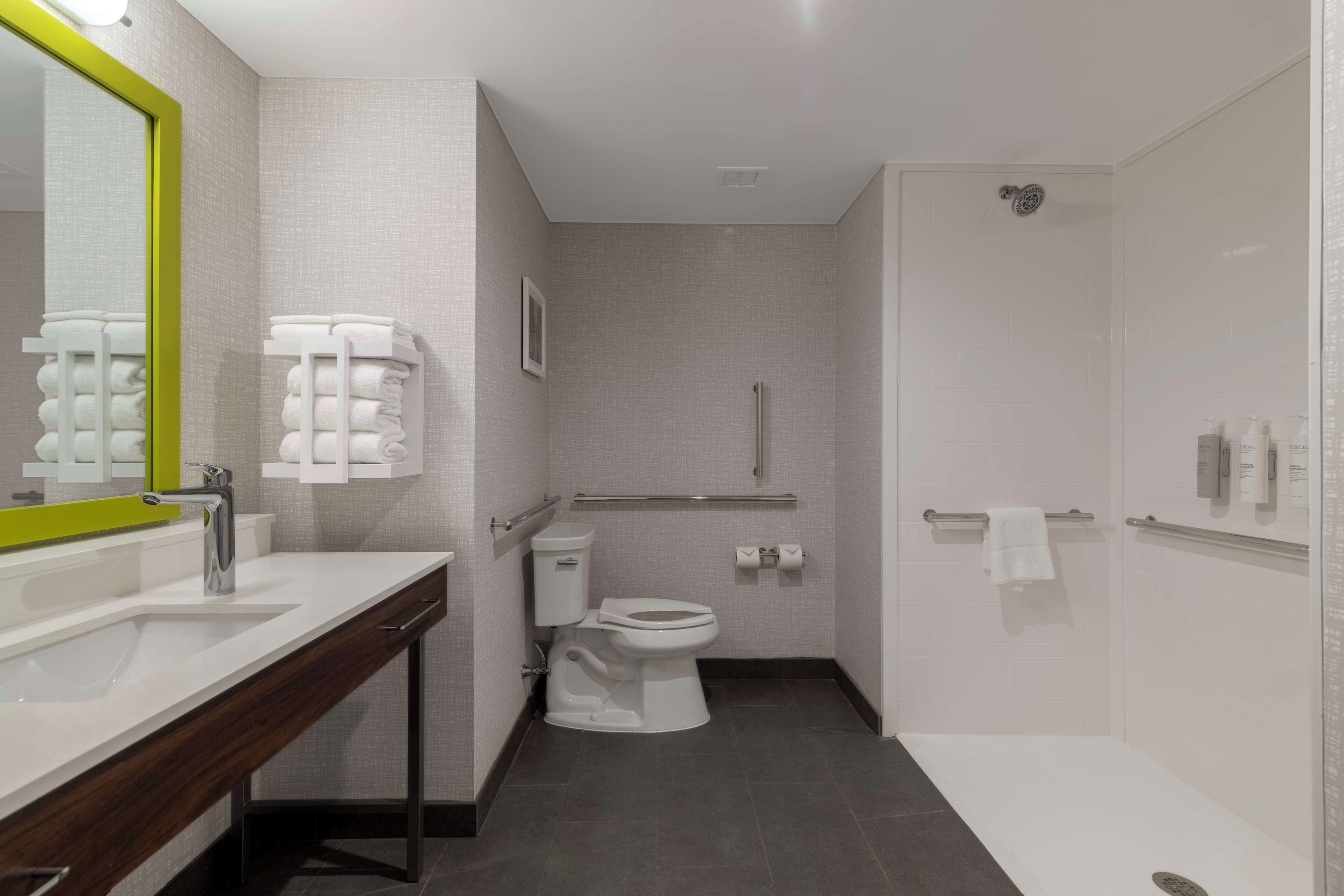 Een moderne badkamer met een wit wastafelmeubel, spiegel, toilet en douche.