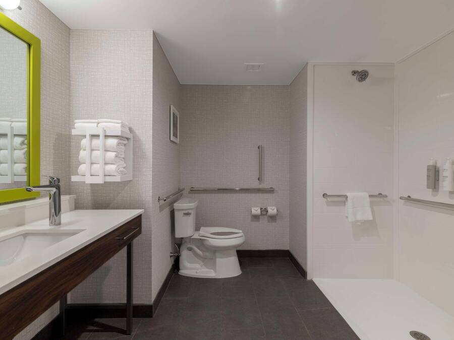 Een moderne badkamer met een wit wastafelmeubel, spiegel, toilet en douche.