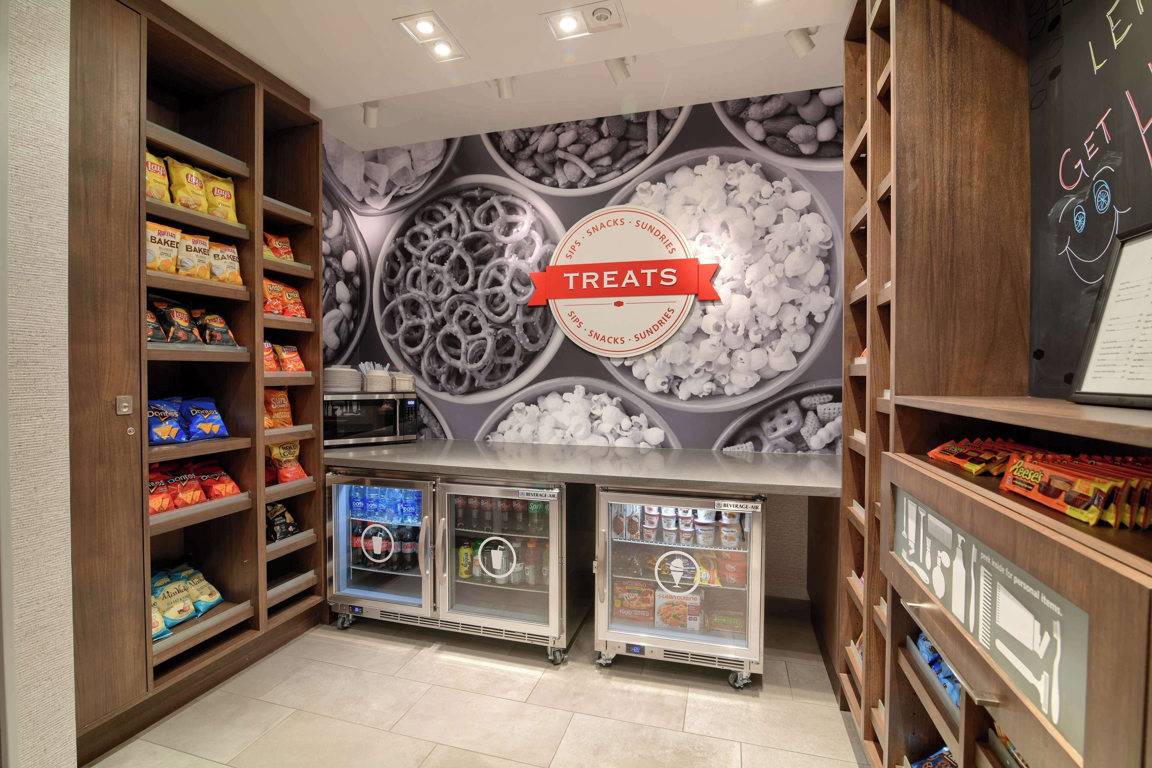 A snack bar area with shelves stocked with various snacks and a refrigerated display case.