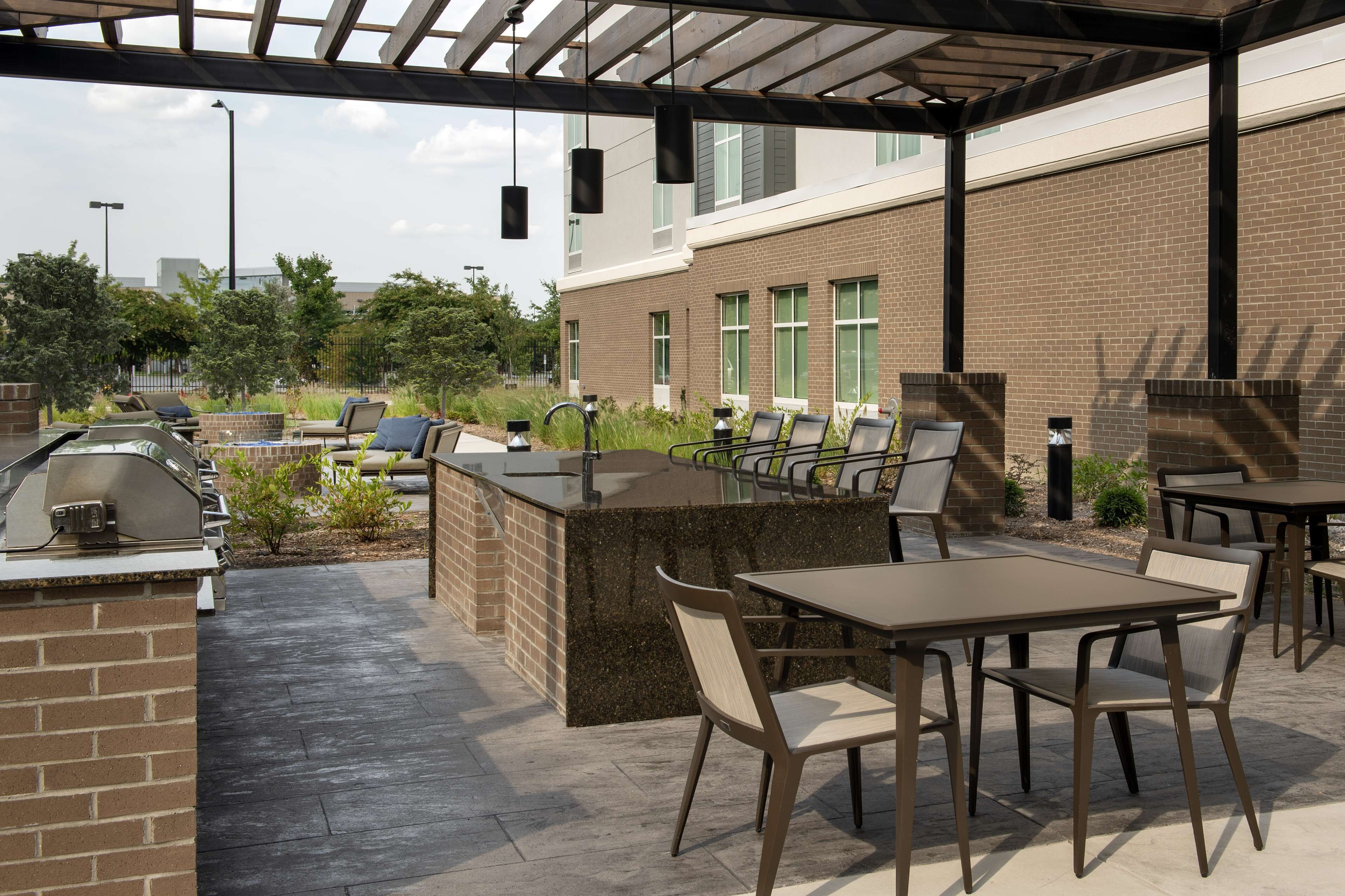 An outdoor patio area with a grill, seating, and a brick wall.