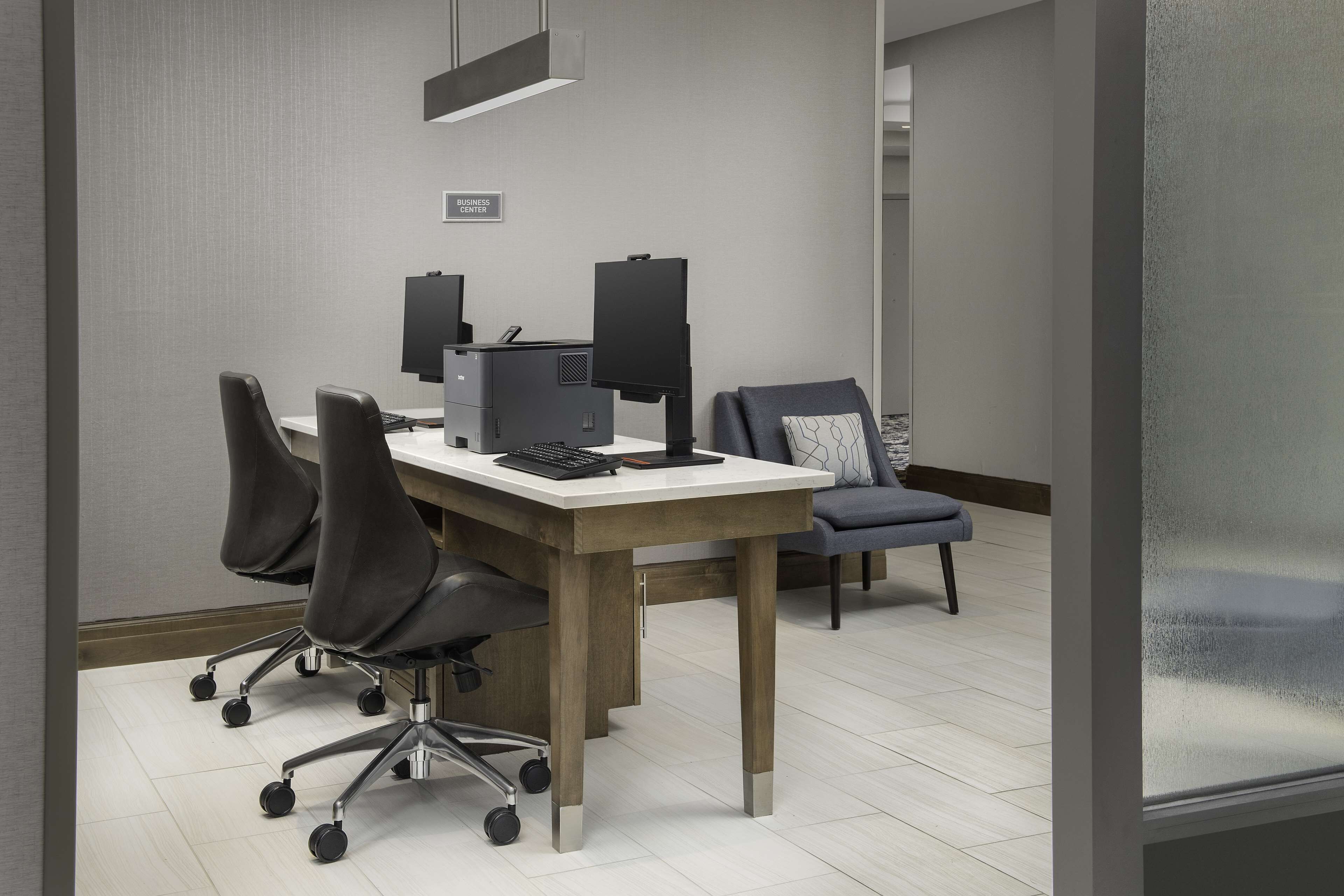 A business center with a desk, computer, and office chairs.