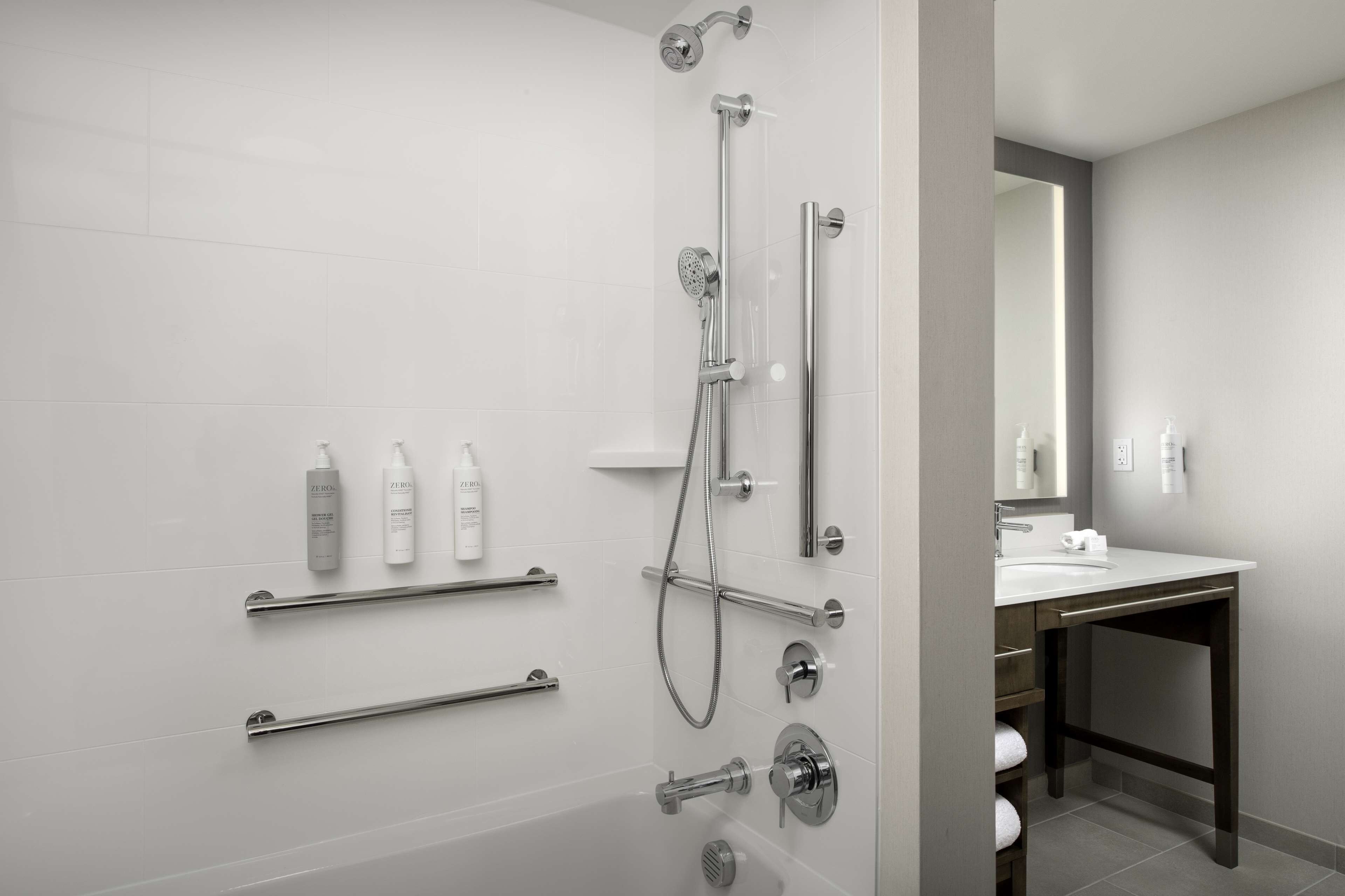 Un baño moderno con ducha a ras de suelo, tocador con espejo y artículos de aseo en la pared.