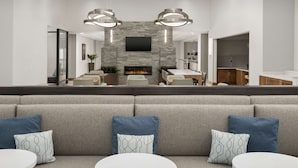 Una sala de estar moderna con chimenea, zona de estar y una cocina al fondo.