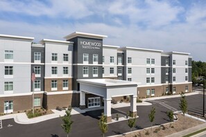 A multi-story hotel with a modern design, featuring a prominent entrance with a covered waiting area and a parking lot. - Homewood Suites By Hilton Greenville, NC (Greenville)