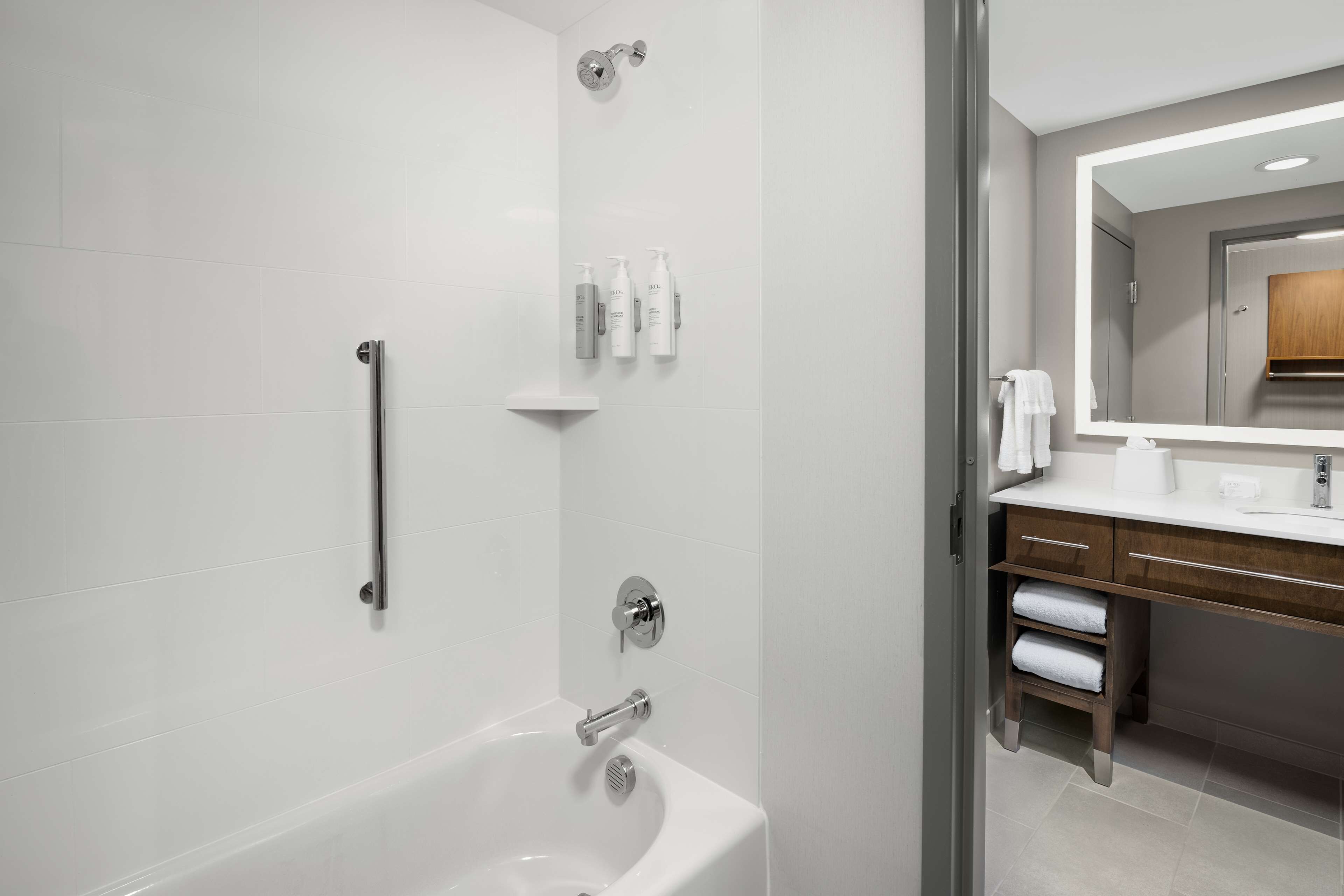 A modern bathroom with a bathtub, a shower, and a vanity with a mirror.