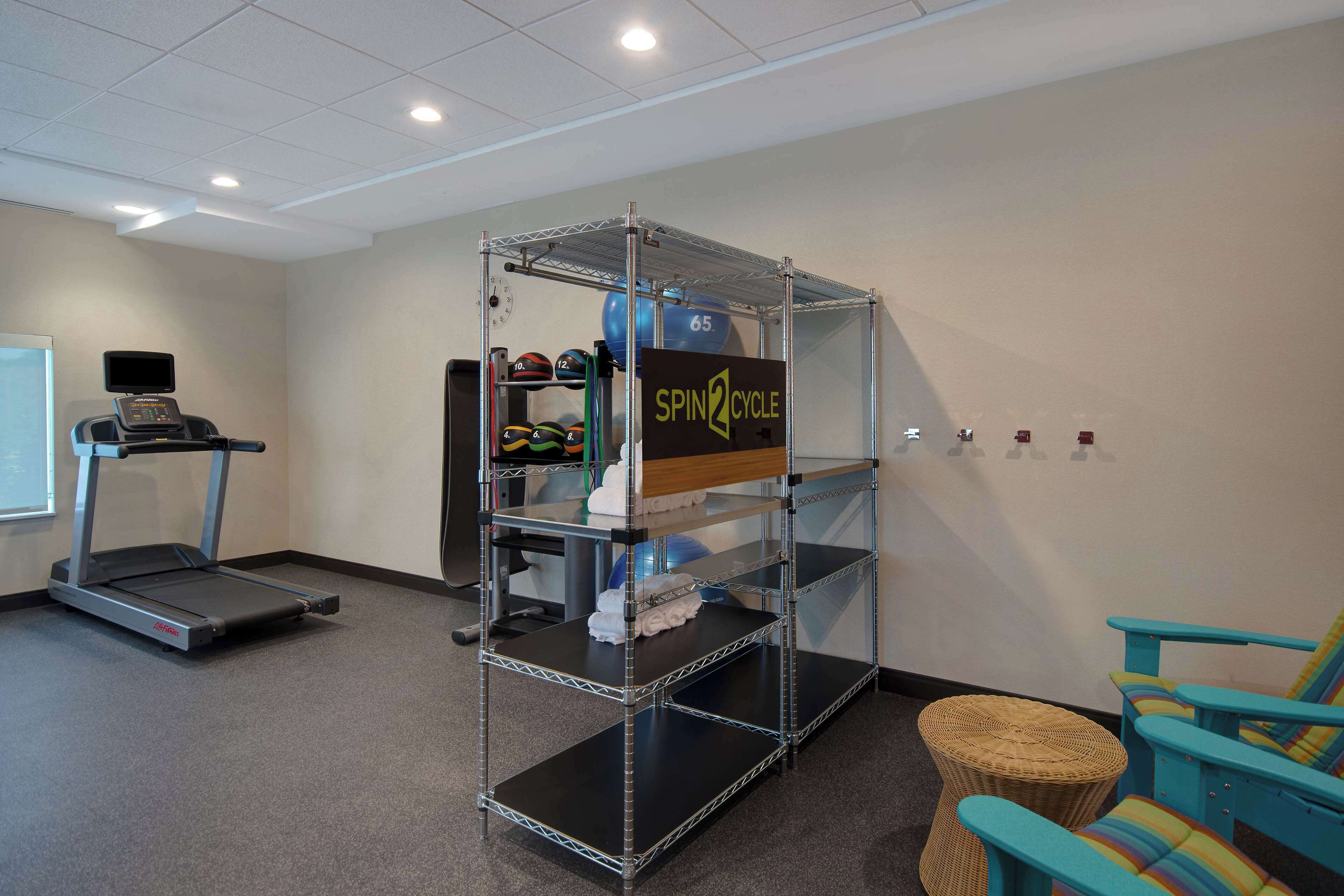 A gym with a treadmill, a spin cycle station, and a blue chair.