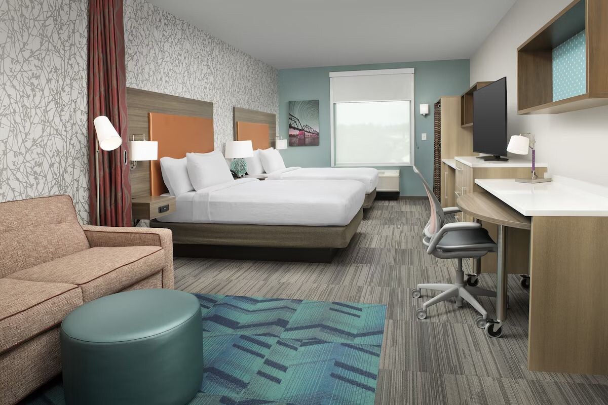 Une chambre d’hôtel comprenant un lit, un bureau, une chaise, un canapé et un téléviseur.