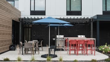 Une terrasse extérieure équipée d’un barbecue, d’une table à manger et de chaises.