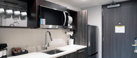 Una cocina moderna con un lavamanos de acero inoxidable, un microondas y un refrigerador.