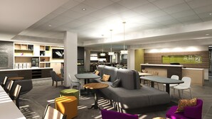 Un moderno vestíbulo de hotel con un área de descanso, una recepción y una cocina al fondo.