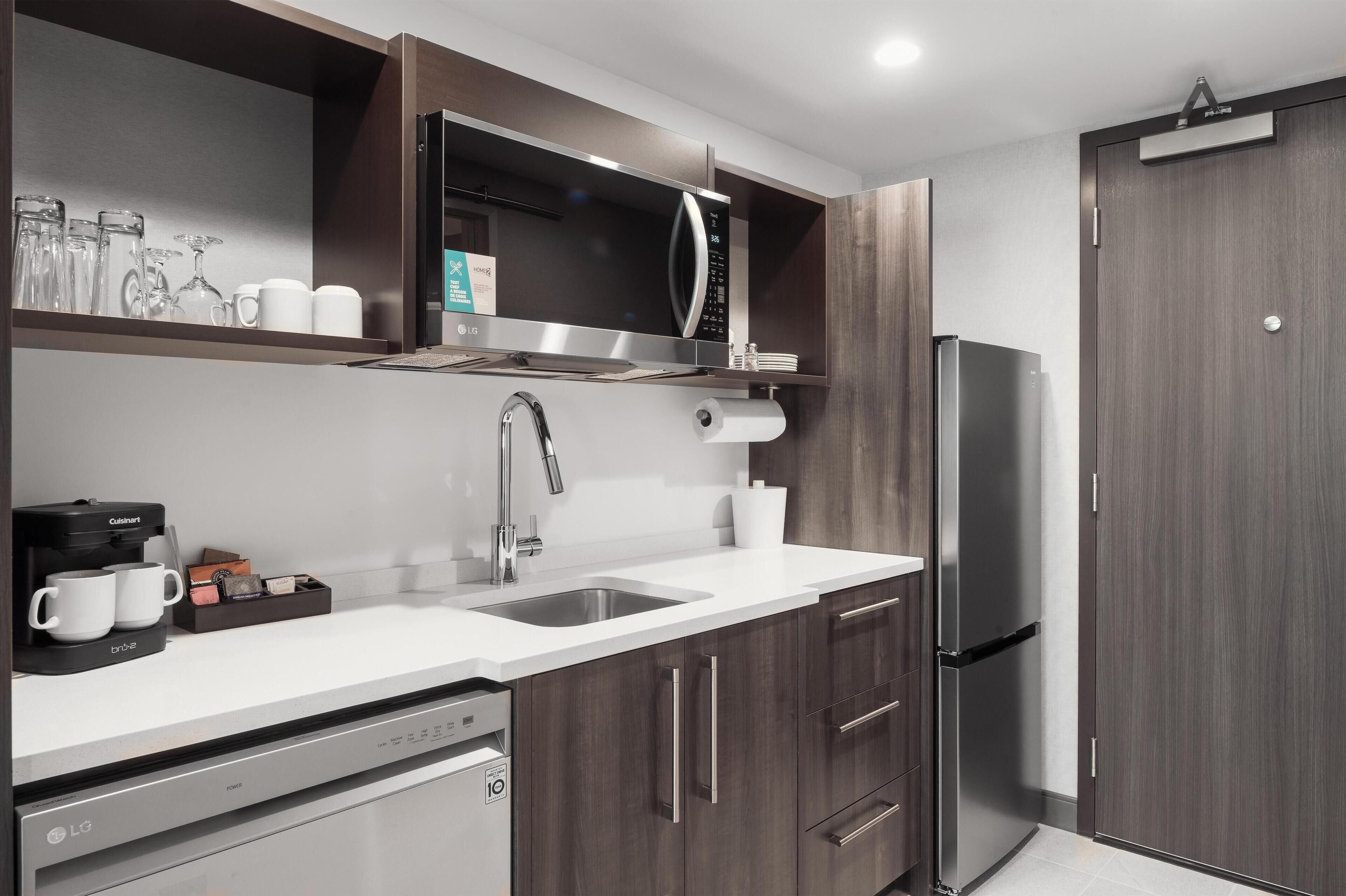 A modern kitchen with a built-in dishwasher, a stainless steel refrigerator, and a microwave.