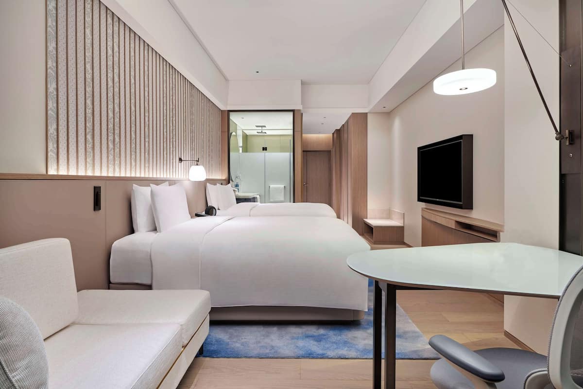 Una habitación de hotel moderna con una cama grande, un sofá, un escritorio y un televisor.
