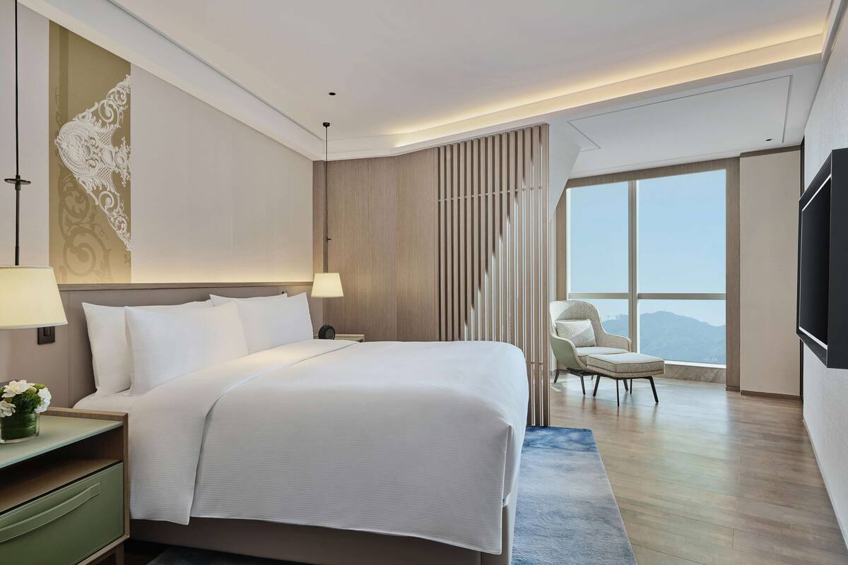 Una habitación de hotel moderna con una cama grande, un escritorio, una silla y un televisor.