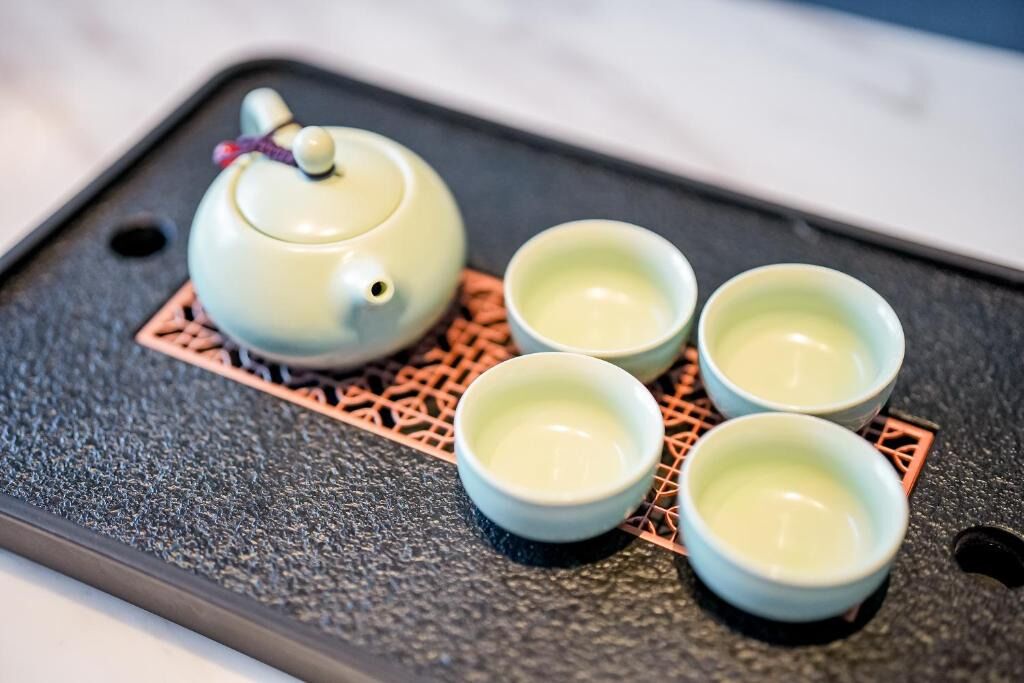 A teapot and four cups on a tray.
