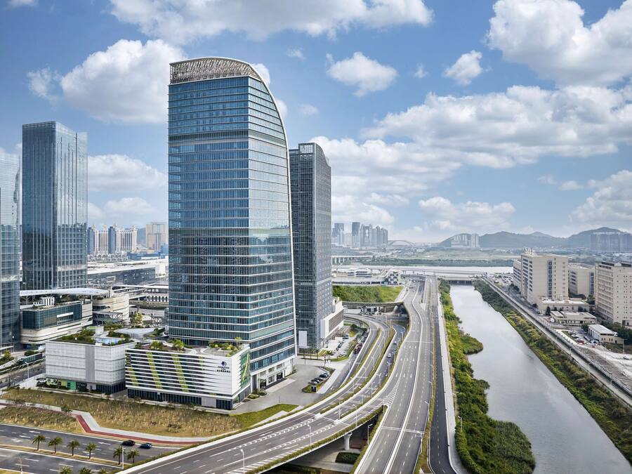 A modern urban landscape with high-rise buildings, a river, and a highway.