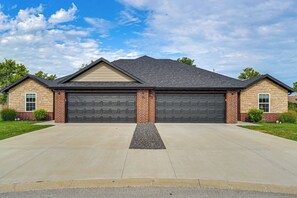 Une maison à deux étages avec un garage, une allée et une pelouse bien entretenue.