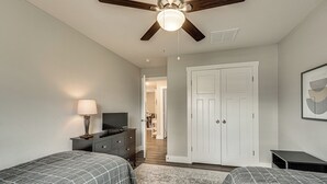 A bedroom with two beds, a dresser, a TV, and a ceiling fan. - Charming Ozark Abode w/ Yard & Pool Access (Ozark)