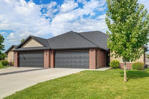 A two-story house with a garage, a stone facade, and a well-maintained lawn.