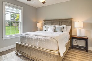 A bedroom with a bed, two bedside lamps, a window, and a wooden headboard. - Family-Friendly Ozark Villa - Centrally Located (Ozark)
