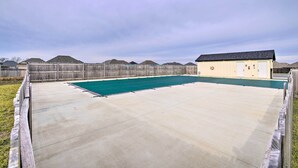 A backyard with a swimming pool, a wooden fence, and a small building with a dark roof. - Family-Friendly Ozark Villa - Centrally Located (Ozark)