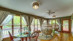 A dining area with a glass table, wicker chairs, and a ceiling fan. - Large Lakefront Home | Pool, Hot Tub & Boat Dock (Grove)