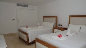 Une chambre d’hôtel avec deux lits, une armoire et une table de chevet avec une lampe.