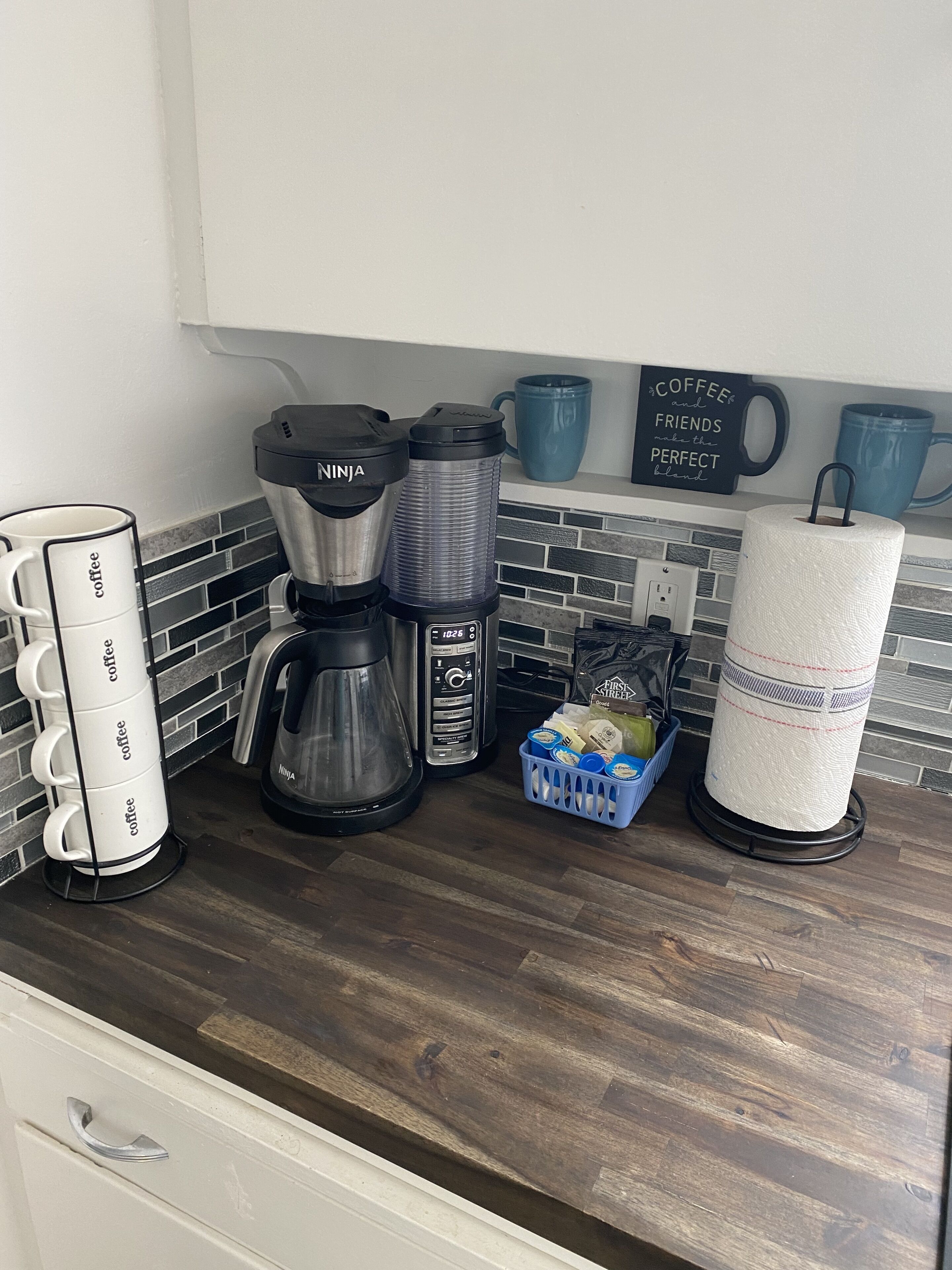 Una cocina con una cafetera, un hervidor y una taza de café sobre la encimera.
