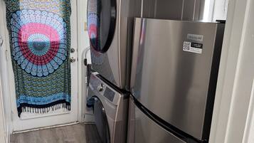 Une cuisine compacte équipée d’un lave-linge, d’un réfrigérateur et d’une porte à motifs.