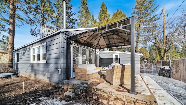 Een gelijkvloers huis met een overdekte patio, schoorsteen en een kleine garage.