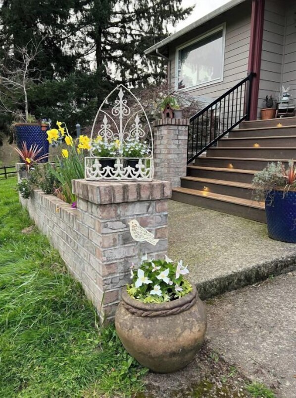 Stroll through the beautifully maintained garden, featuring a stone planter with vibrant flowers and a decorative metal archway.